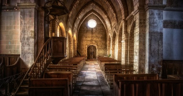 Empty wooden pews inside a stone church