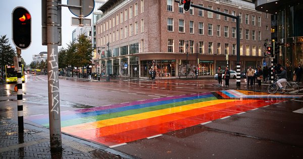 A rainbow-painted pedestrian crossing on a wet city street