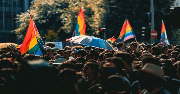 Rainbow flags carried through a crowd at a European Pride march