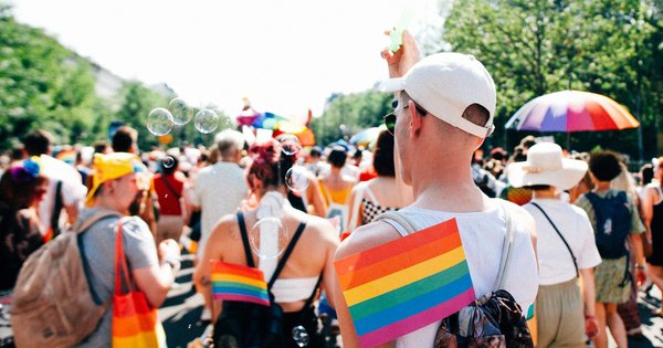 Rainbow flags carried through a city street during a Pride march