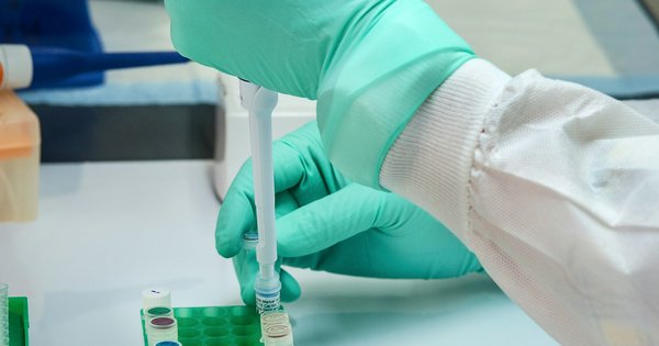 A scientist in gloves works with samples at a laboratory bench