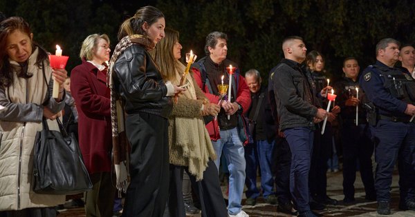 A person holding a lit candle at a nighttime vigil