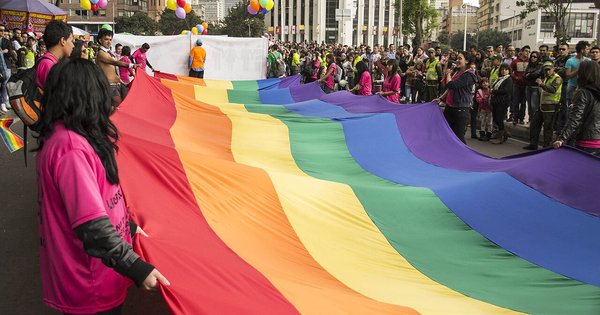 Marchers carry a giant rainbow flag through a street during an LGBT Pride march in Bogotá, Colombia
