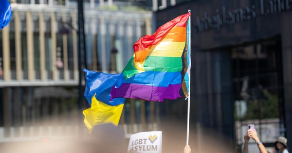 A rainbow flag raised above a crowd at a Pride march