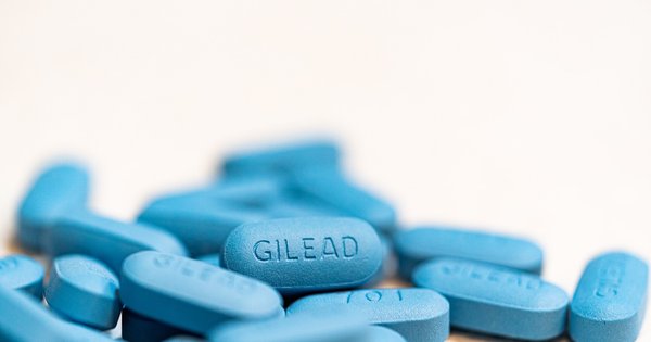 Blue PrEP pills scattered next to a prescription bottle on a table