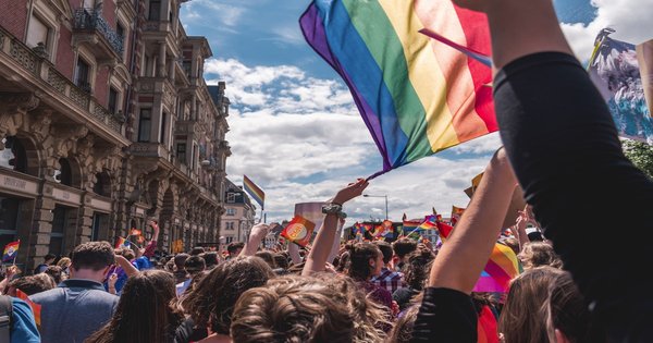 A crowd holding a large rainbow flag at a Pride parade