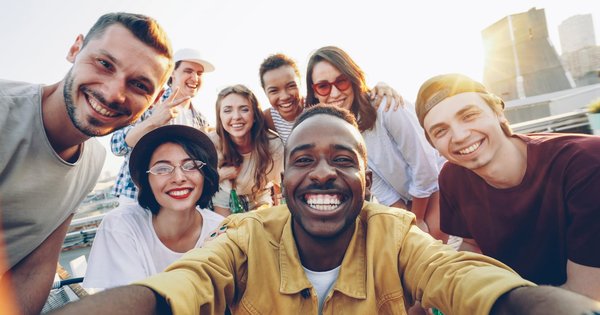 A diverse group of young adults smiling together outdoors