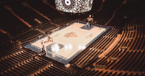 A basketball resting at center court under arena lighting