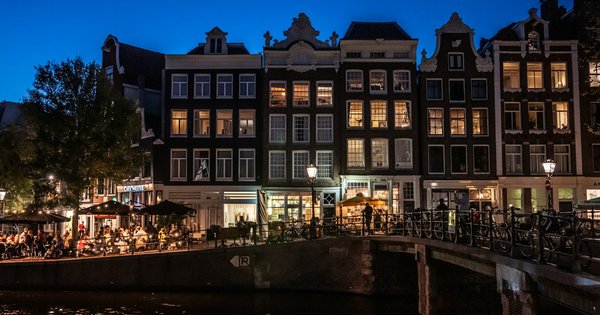 Canal houses reflected in an Amsterdam canal at dusk