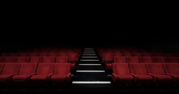 Rows of red cinema seats in a dark movie theater