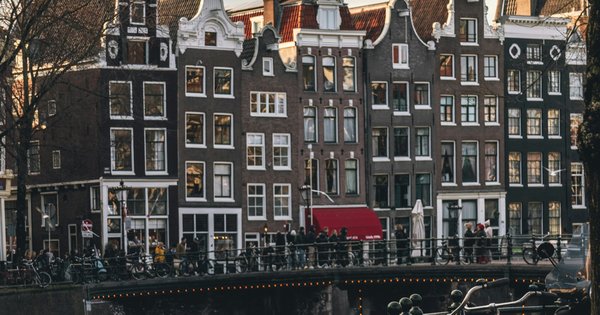 A row of bicycles parked along a canal in a Dutch city