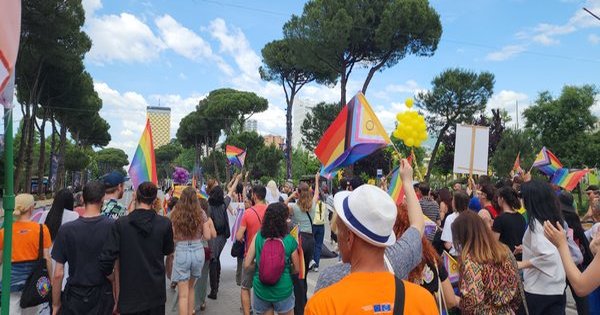 A large crowd of Pride marchers waving rainbow flags