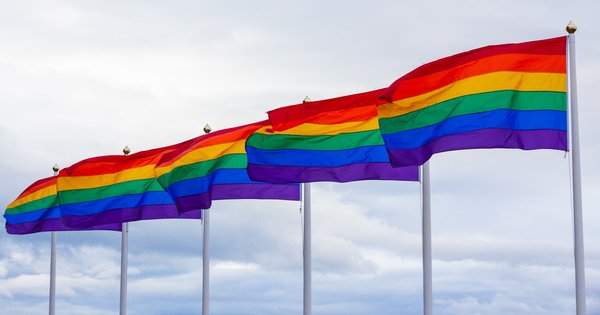 A rainbow pride flag flying against a clear sky