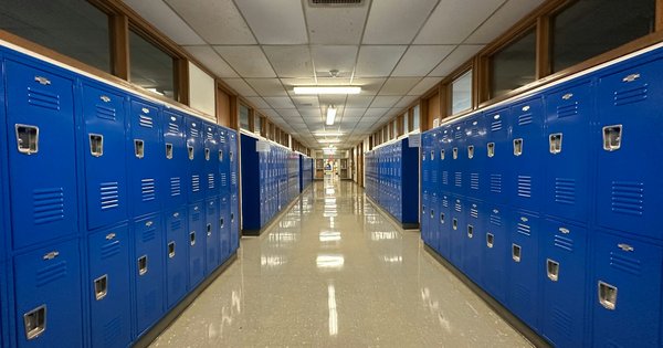 A long, empty school hallway lined with bright blue lockers on both sides