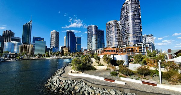 Perth city towers rise above the Swan River waterfront at Elizabeth Quay on a sunny day