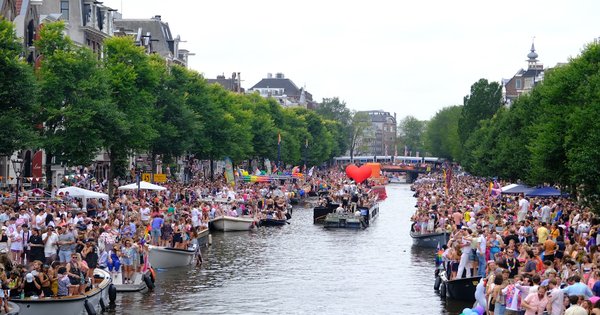 Rainbow flags and crowds along an Amsterdam canal during a pride celebration